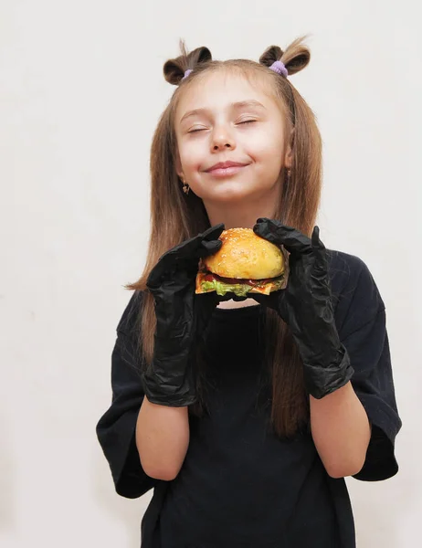 Schattig Klein Meisje Met Zwart Handschoenen Eet Hamburger — Stockfoto