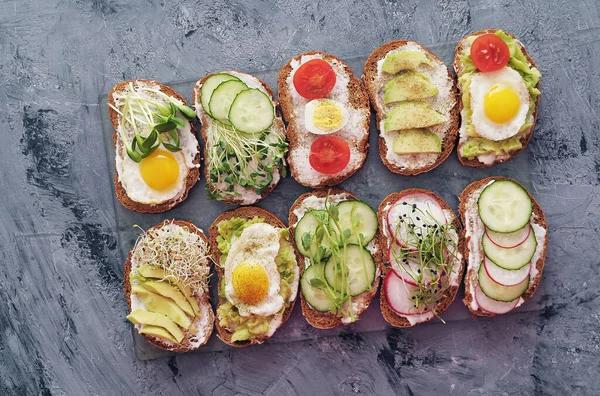 Sandwiches with vegetables, eggs, avocado and micro greens on stone background. Healthy food.