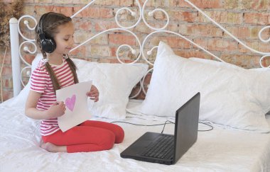 Küçük kız deftere bakar ve kağıda çizilmiş bir kalp gösterir..