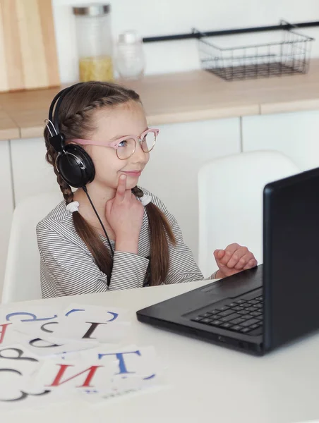 Girl with laptop and headphones at home school education. Online learning.