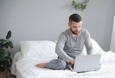 Yataktaki adam evde çalışıyor. Uzaktan çalışma konsepti. Evden çalış..
