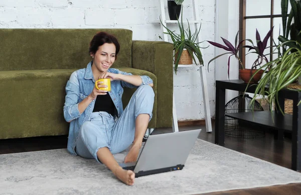 Smiling woman works with laptop at home. Remote work concept. Work from home.