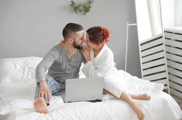Man and woman communicate in laptop. Happy family in the morning in bed at home.