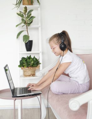 Ev okulunda bilgisayar ve kulaklık takan bir kız. Onling öğrenme.