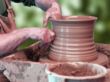 Bir çömlekçi elinde bir yeşil zemin üzerine seramik direksiyona yaparım.