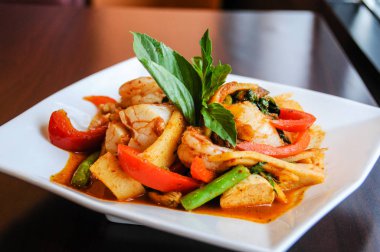 Tavada kızartılmış Baharatlı deniz ürünleri, tavada kızartılmış karides, midye, midye, mürekkep, Yengeç, Balık topları, bambu sürgünleri, yeşil fasulye, fesleğen yaprakları ve patlıcan ile kırmızı köri.