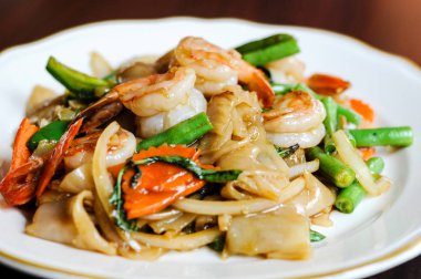 Pad Khee tavada kızartılmış geniş pirinç noodle, sıcak biber, havuç, yeşil fasulye, soğan, Mao, domates ve fesleğen yaprakları.