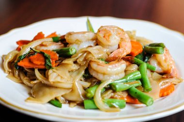 Pad Khee tavada kızartılmış geniş pirinç noodle, sıcak biber, havuç, yeşil fasulye, soğan, Mao, domates ve fesleğen yaprakları.