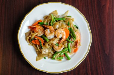 Pad Khee tavada kızartılmış geniş pirinç noodle, sıcak biber, havuç, yeşil fasulye, soğan, Mao, domates ve fesleğen yaprakları.