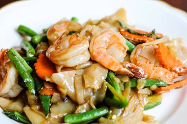 Pad Khee tavada kızartılmış geniş pirinç noodle, sıcak biber, havuç, yeşil fasulye, soğan, Mao, domates ve fesleğen yaprakları.