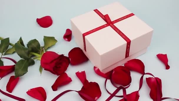 明るい背景に赤いバラとバラの花びら バレンタインデー 愛の概念 男性の手は白い箱を開ける 箱の中の赤いハート — ストック動画