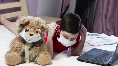 Corona virüsü. Çocuk internetten iletişim kuruyor. Maskeli çocuk. Maskeli ayı. Dersler uzak. Karantina