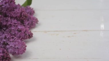 Beyaz ahşap arka planda bir fincan kahve ve leylak. Kahve dolduruldu.