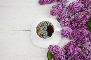 Bir fincan sıcak kahve. Beyaz ahşap arka planda koyu bir kahve. Sabah kahvesi. Cappuccino kahve ve leylak. Yukarıdan bak. Kopyalama alanı