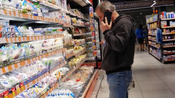 제품의 슈퍼마켓 남자가 전화나 아이폰으로 이야기하고 있습니다 상품을 선택하라 — 비디오