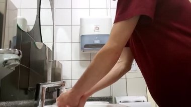 Tuvalette ellerini yıkayan bir adam var. Kuru eller. El dezenfeksiyonu. COVID-19