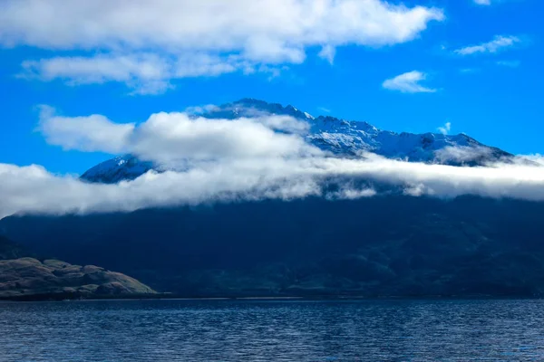 雪と水の間の白い雲を頂いた山を背景 — ストック写真