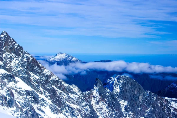 雪をかぶった山々 の低い白い雲 — ストック写真