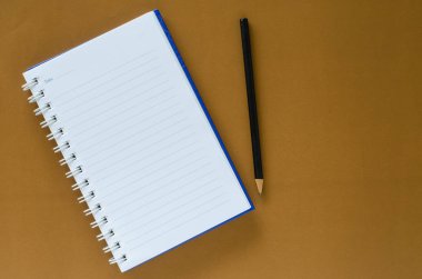 Beyaz not defteri ve kahverengi renk zemin üzerine siyah kalem 