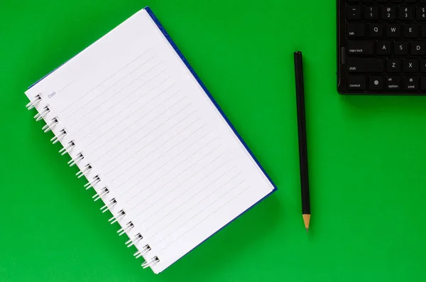 Cuaderno blanco y lápiz negro y teclado negro en col verde —  Fotos de Stock