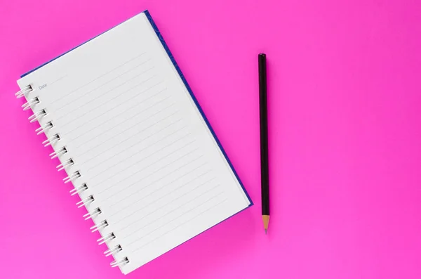 White note book and black pencil on pink color background with c Stock Image