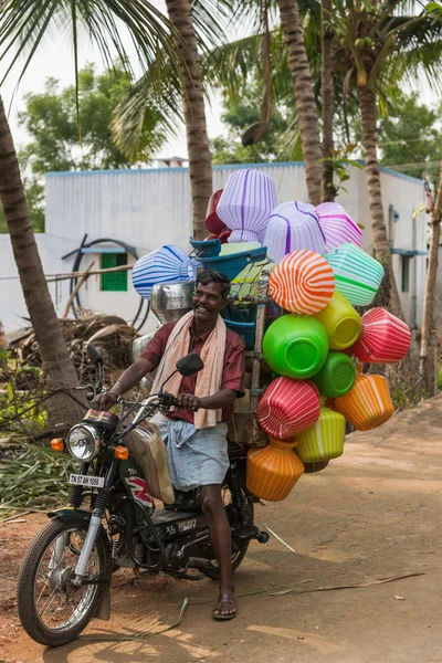 Vendedor ambulante em sua moto vendendo frascos de plástico . — Fotografia de Stock