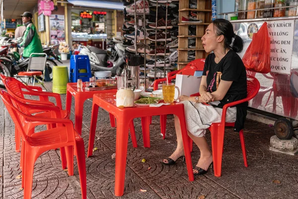 Γυναίκα τρώει μεσημεριανό κάθεται σε κόκκινη καρέκλα στο Ho Chi Minh City, Vietn — Φωτογραφία Αρχείου