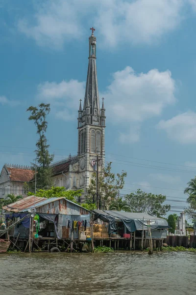 Shops on stilts in canal in front of Catholic church of Cai Be, — Stock Photo, Image