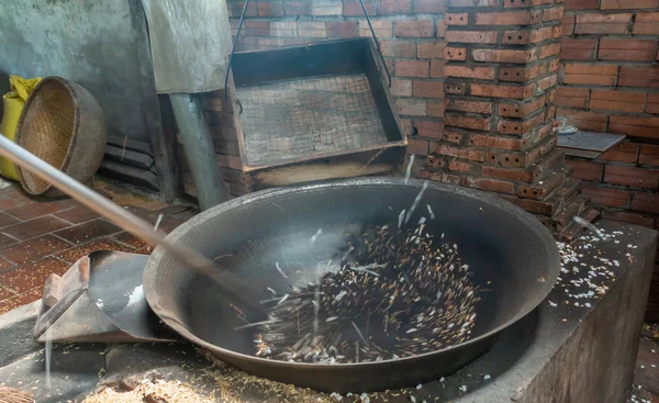 Blackened rice kernels start to pop in black heated basin in Cai — ストック写真