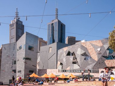 Federasyon meydanı, Melbourne 'daki Acmi binasıyla güneşte pişiyor.,