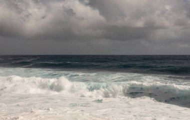 Kara okyanus Kaimu 'da ağır bulutlar altında beyaz sörflere dönüşür.