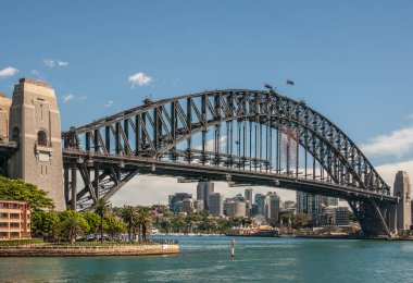 Sydney, Avustralya - 11 Aralık 2009: Harbour Köprüsü, mavi gökyüzüne ve gök mavisi körfez sularının üzerine karşı tam metal açıklık, yay ve taş çapa kuleleri. Kuzey Sydney ve Luna Park 'ın yüksek binaları.