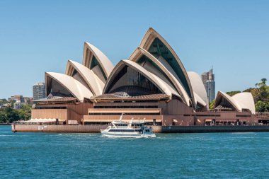 Sydney, Australia - December 11, 2009: Opera House. Frontal water-level closeup of it and white Matilda ferry boat in front under blue sky. Azure bay water in front.