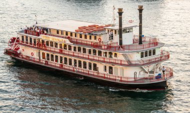 Sydney, Australia - December 11, 2009: Sunset colors water a shiny silver. Closeup of beige-red Mississippi style river steam Showboat with people on deck. 