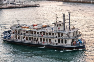 Sydney, Australia - December 11, 2009: Sunset colors water a shiny silver. Closeup of beige-brown Mississippi style river steamboat Harbour Ballroom with people on deck on Walsh Bay. 