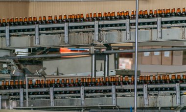 Brisbane, Australia - December 8, 2009: 2 transport belt moving brown full beer bottles to the labeling machine. Gray metal machines. 