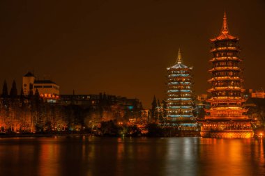 Guilin, China - May 9, 2010: Riyue Shuangta Cultural Park. Wide shot on the  Twin Pagodas in Shanhu Lake, the silver and the gold, under pitch black night. Their lights reflected in water. 