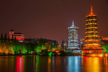 Guilin, China - May 9, 2010: Riyue Shuangta Cultural Park. Wide shot on the Twin Pagodas in Shanhu Lake, the silver and the gold, under pitch black night. Their lights reflected in water. 