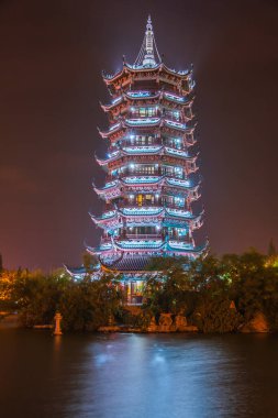 Guilin, China - May 9, 2010: Riyue Shuangta Cultural Park. Closeup Portrait of silver Pagoda in Shanhu Lake under pitch black night. Lights reflected in water. 