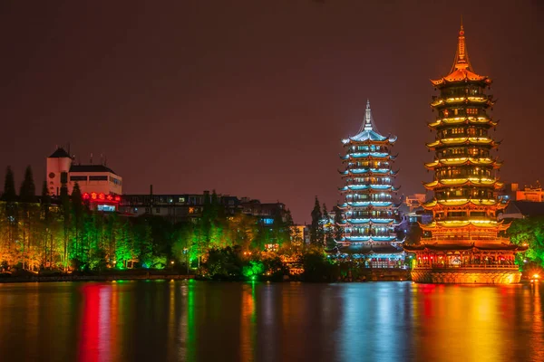 Guilin, China - May 9, 2010: Riyue Shuangta Cultural Park. Wide shot on the Twin Pagodas in Shanhu Lake, the silver and the gold, under pitch black night. Their lights reflected in water. 
