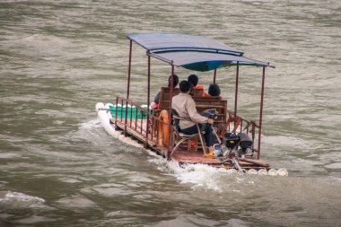 Guilin, China - May 10, 2010: Along Li River. Closeup of 4-person small ferry boat, a raft with a motor, on greenish water.