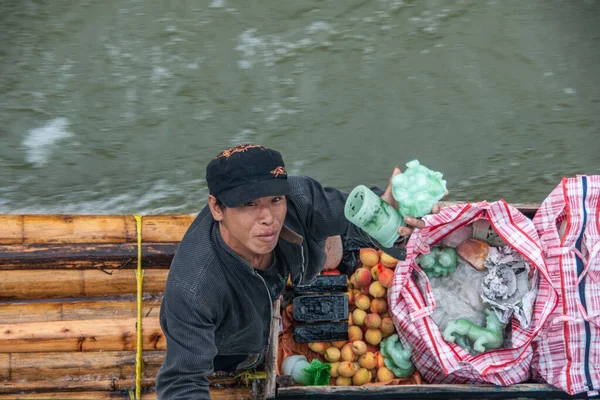 2010年5月10日 李川で 男性のベンダーは 観光船の観光客に緑の人工物と黄色の赤いリンゴを売ります 彼は緑の水に浮く筏の上に立つ — ストック写真