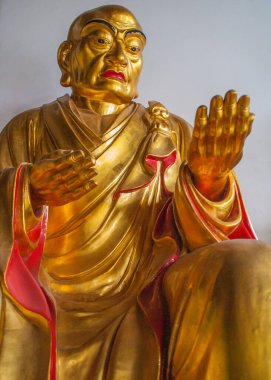 Guilin, China - May 11, 2010: Qixia Buddhist Temple in Seven Star Park. Chest closeup of Golden statue of arhat, Chinese Buddhist saint. against blue blackdrop.