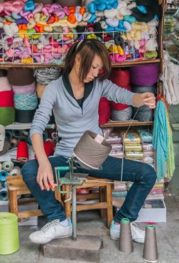 Guilin, Çin - 11 Mayıs 2010: şehir merkezi. Genç bir kadın ipe manuel olarak tutunuyor. İpliklerle dolu rafların renkli arkaplanı.