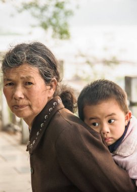 Guilin, Çin - 11 Mayıs 2010: şehir merkezi. Kahverengi elbiseli büyükannenin küçük çocuğu sırtında taşıdığı yakın plan..