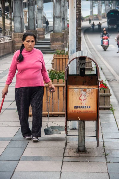 中国桂林 2010年5月11日 市中心 身穿粉色和黑色衣服的妇女手持清扫街道的工具 站在棕色城市垃圾旁边 沿着街道站着 — 图库照片