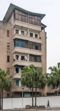 Guilin, Çin - 11 Mayıs 2010: şehir merkezi. Gümüş gökyüzünün altında küçük daireleri ve balkonları olan bej renginde bir apartman. Yeşil palmiye ağaçları olan cadde.