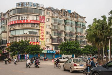 Guilin, Çin - 11 Mayıs 2010: şehir merkezi. Meşgulüm. Ve geniş kavşakta araba ve scooter trafiği var. Yeşil ağaçlar ve yedi katlı binalarda büyük Mandarin sembolleri var..