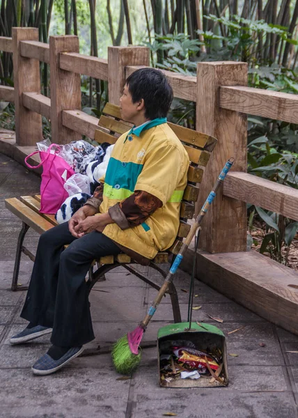 中国重庆 2010年5月9日 身穿黄色背心和黑色裤子的扫街女工在长椅上休息片刻 她的扫帚和收集桶就在身边 — 图库照片