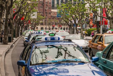 Şangay, Çin - 4 Mayıs 2010: Tüm yeşil kullanılabilirlik ışığı açık olan taksilerle dolu cadde kapatıldı. Arkaplan olarak yeşil yapraklar ve kahverengi binalar.